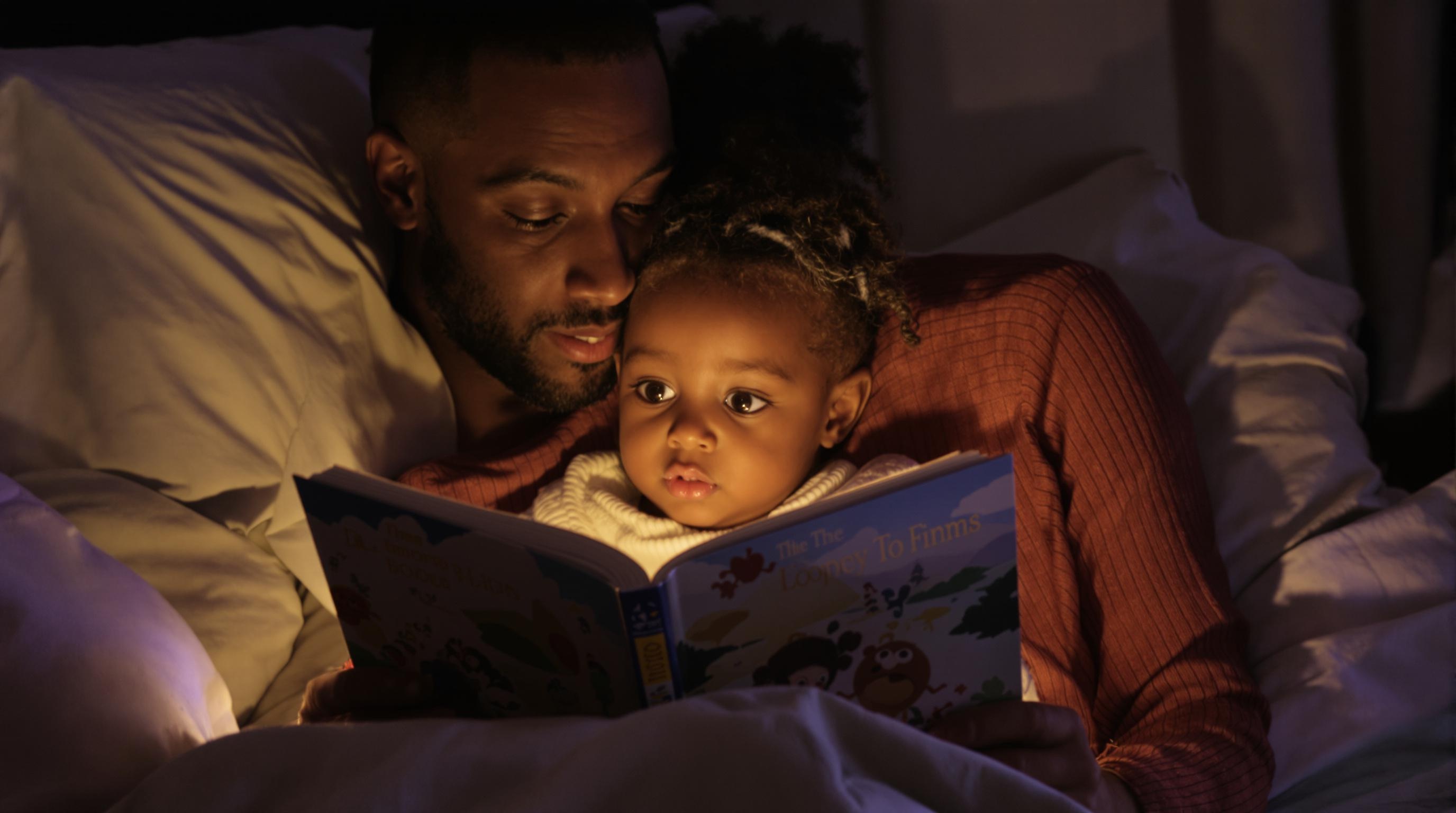 Un parent lisant un livre à son enfant avant de dormir.