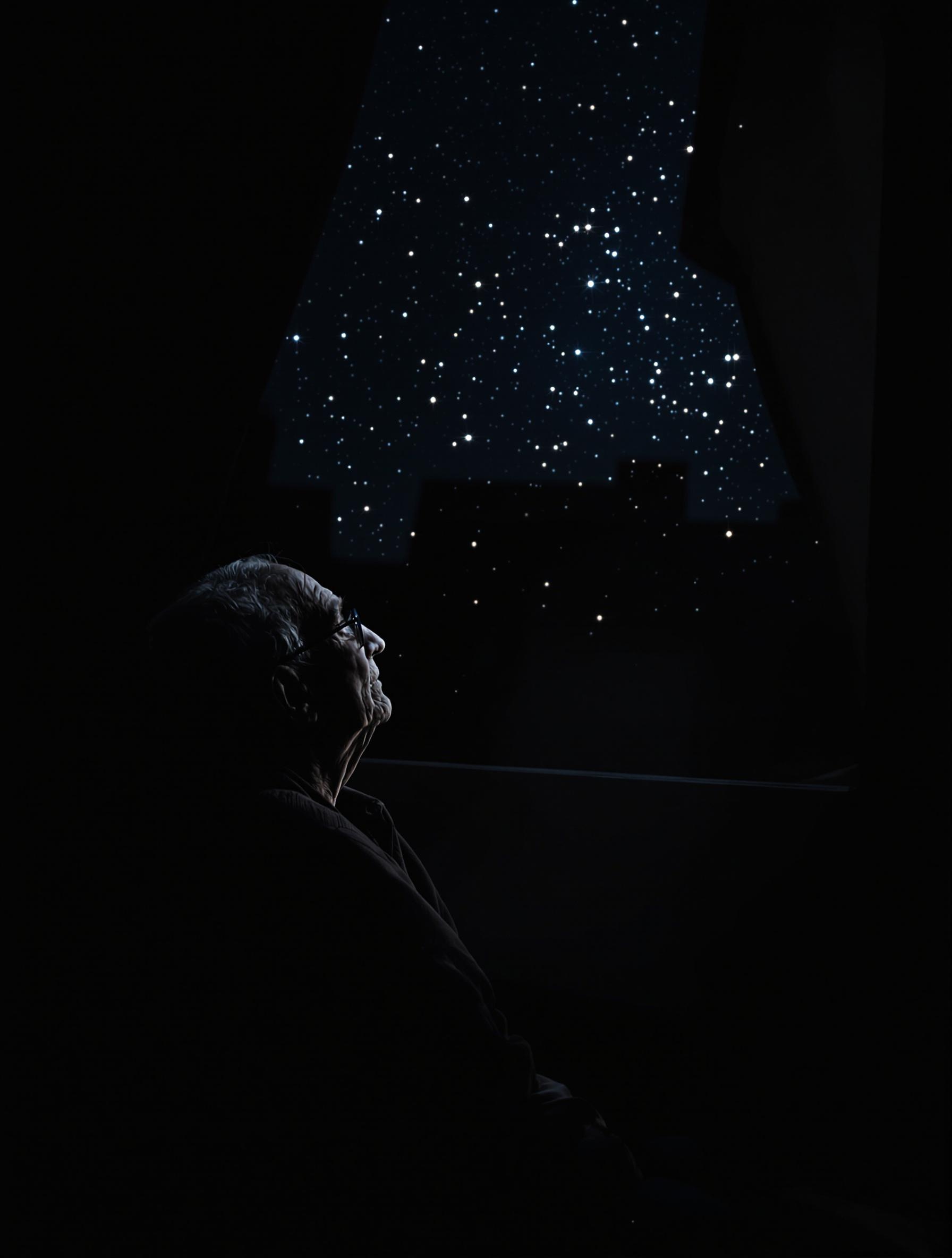 Une personne âgée regardant par la fenêtre la nuit.